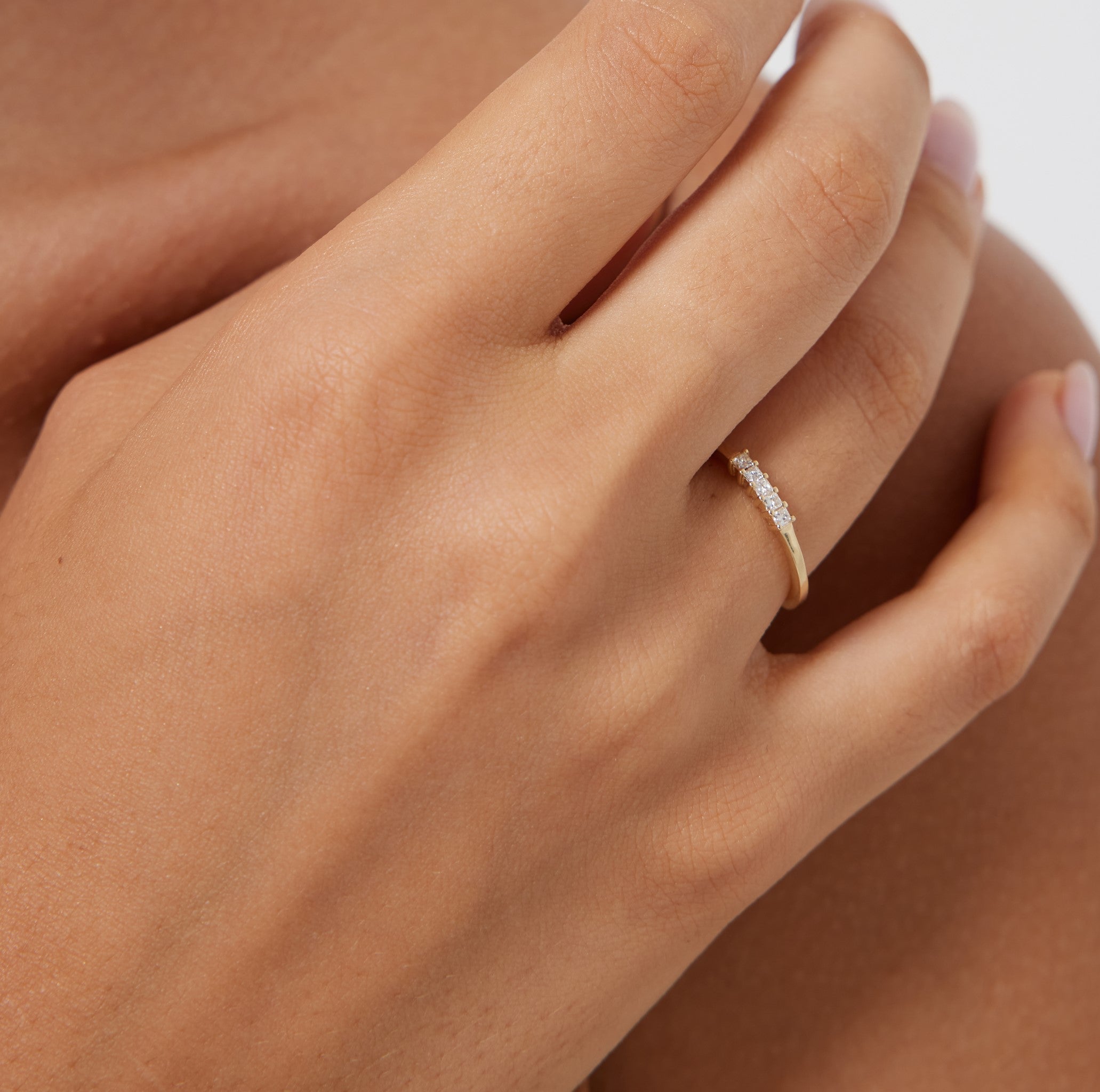 14K gold princess cut diamond wedding ring worn on hand, featuring five brilliant diamonds with a shiny finish.