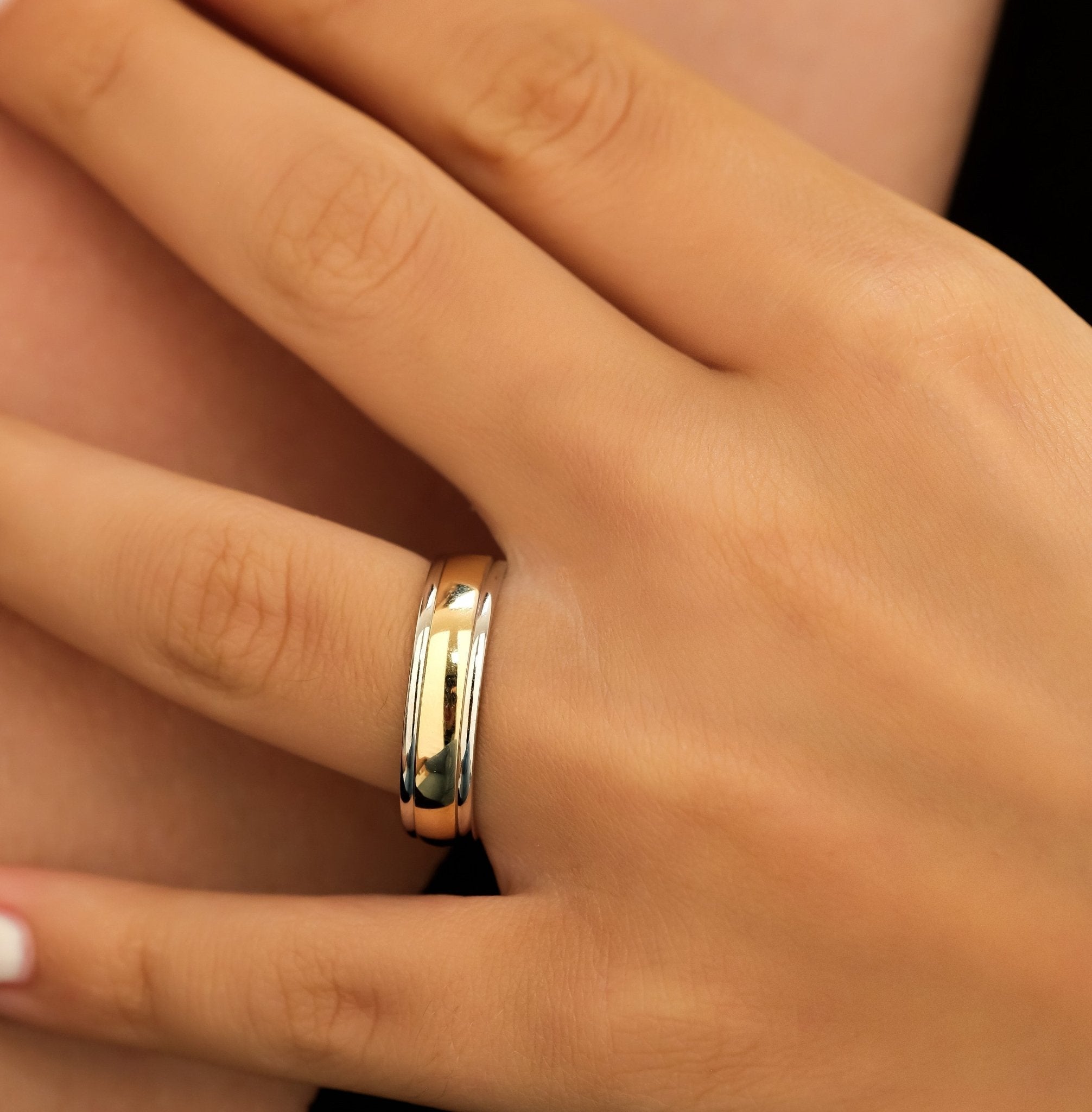 Two tone gold men's wedding band on hand, showcasing shiny yellow gold and white gold design.